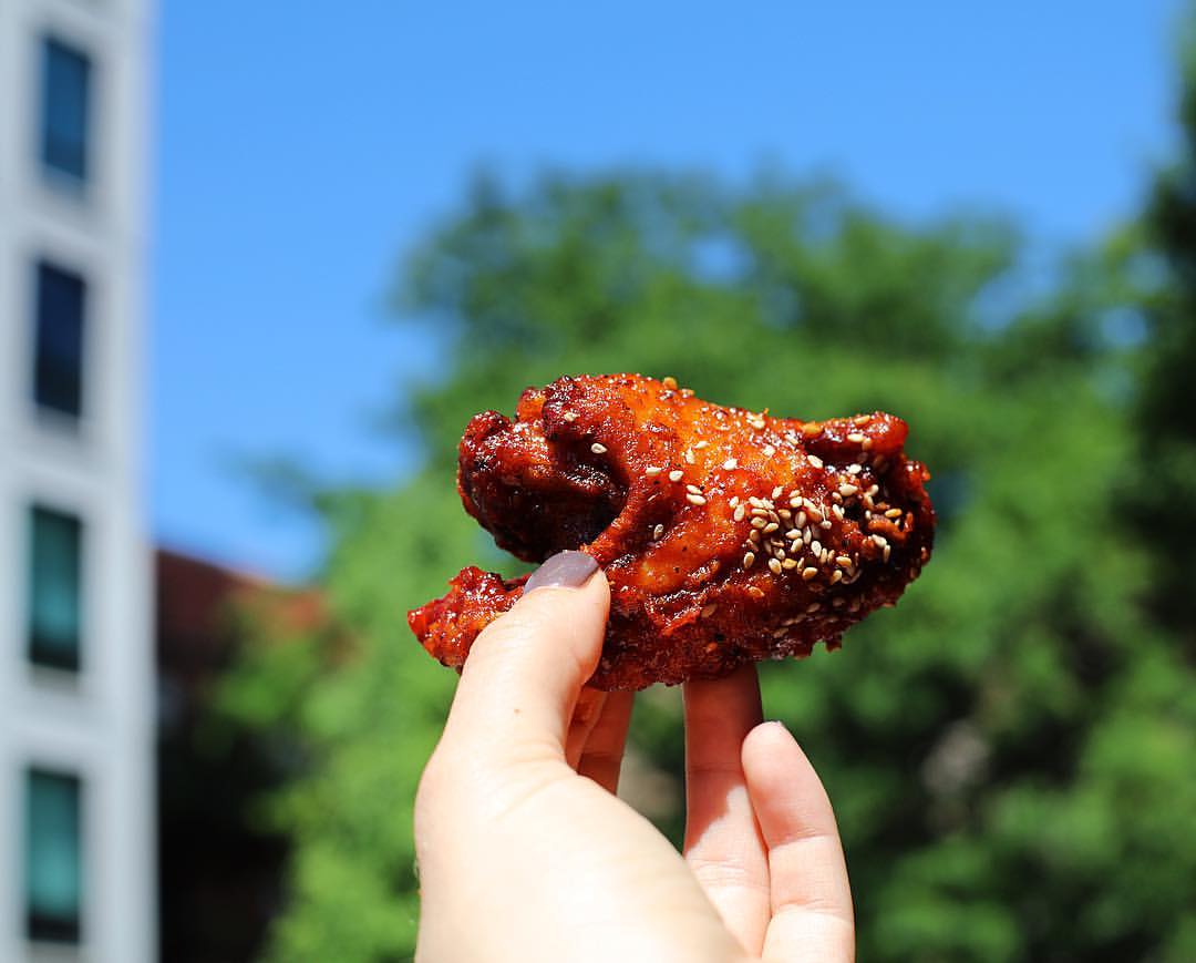 a woman holding a crispy chicken wing in Chicago