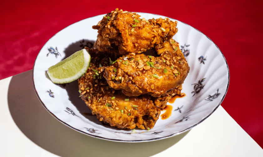 a white plate with crispy chicken wings and a red background